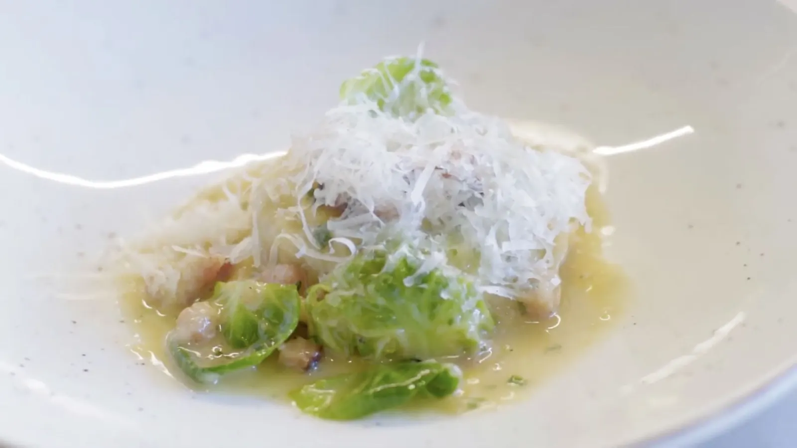A pasta dish topped with shaved cheese