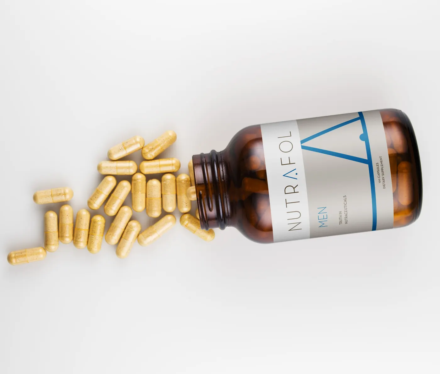 Nutrafol capsules spilling from an amber bottle