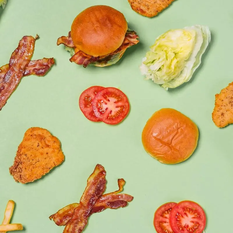 Burger ingredients laid out on a mint background