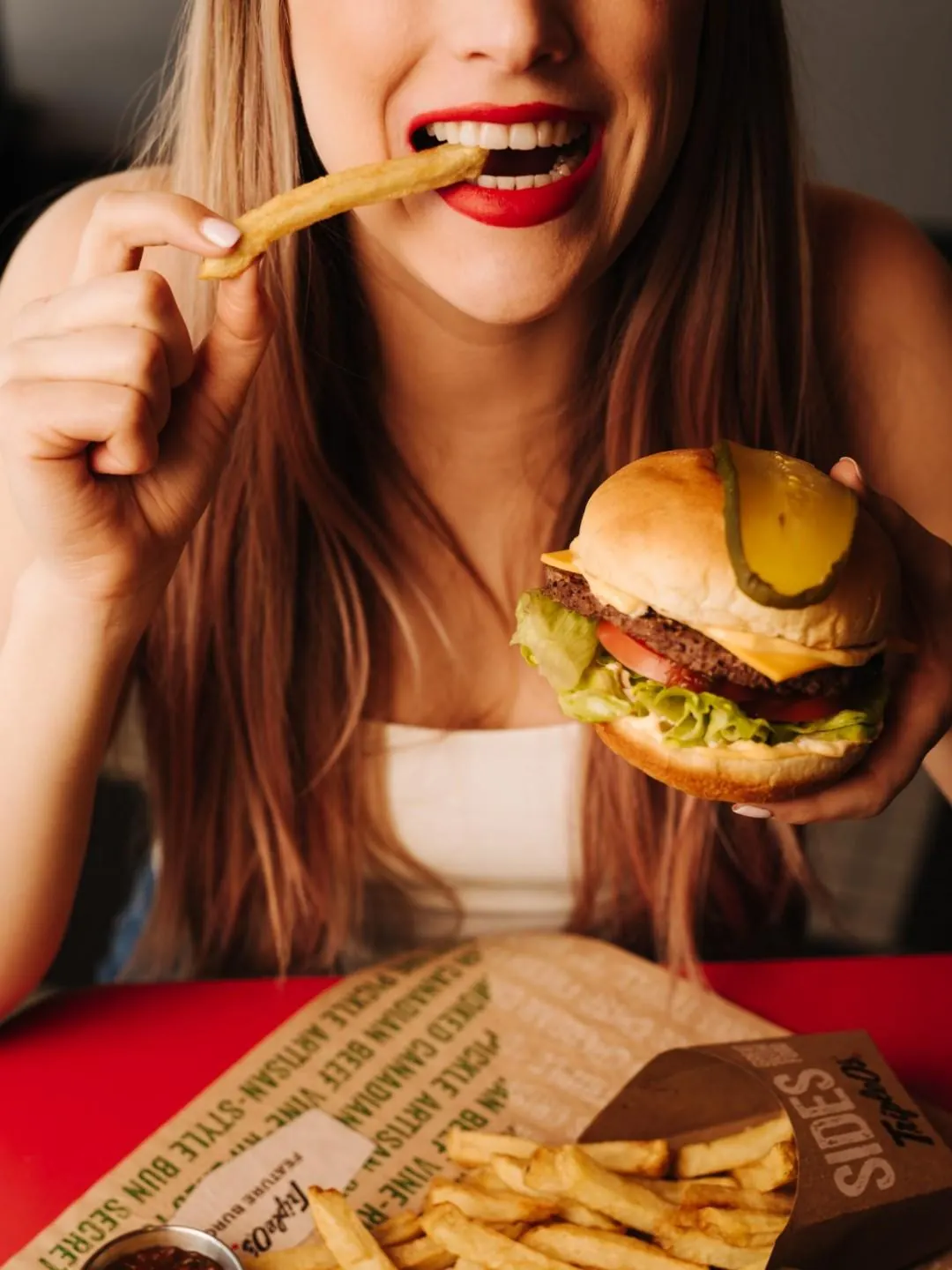 A woman eating fries and a burger